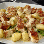 Skillet of creamy chicken and gnocchi in a rustic Italian kitchen.